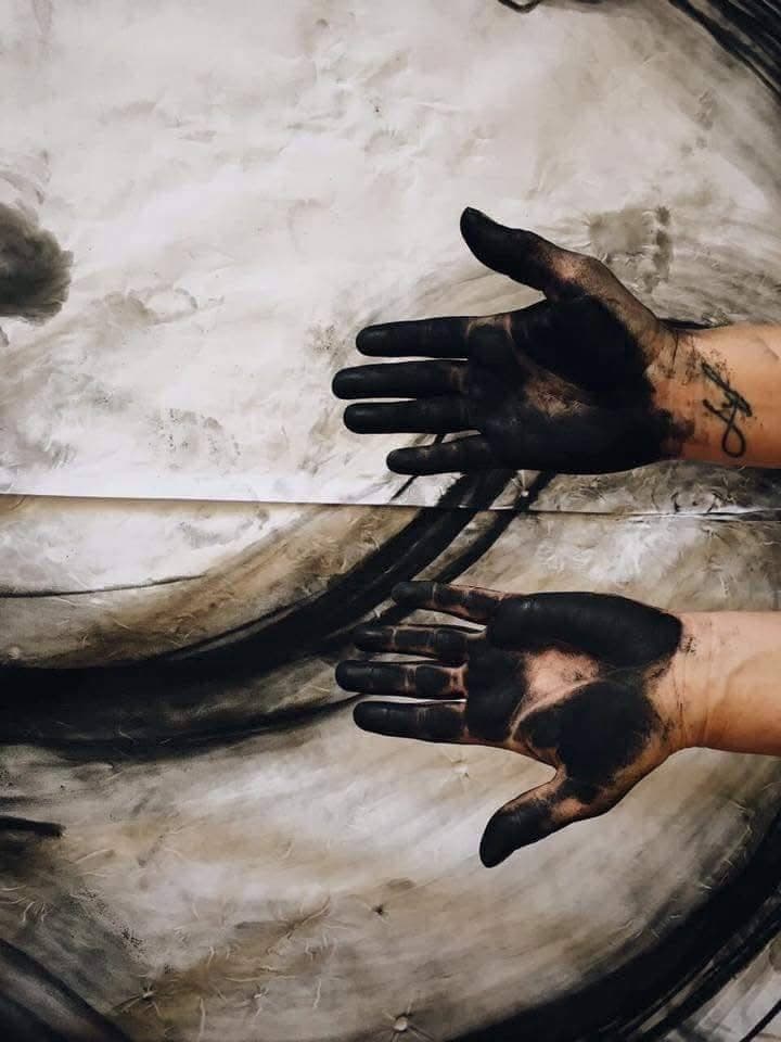 Two ink-stained hands held open toward the camera, photographed in black and white.